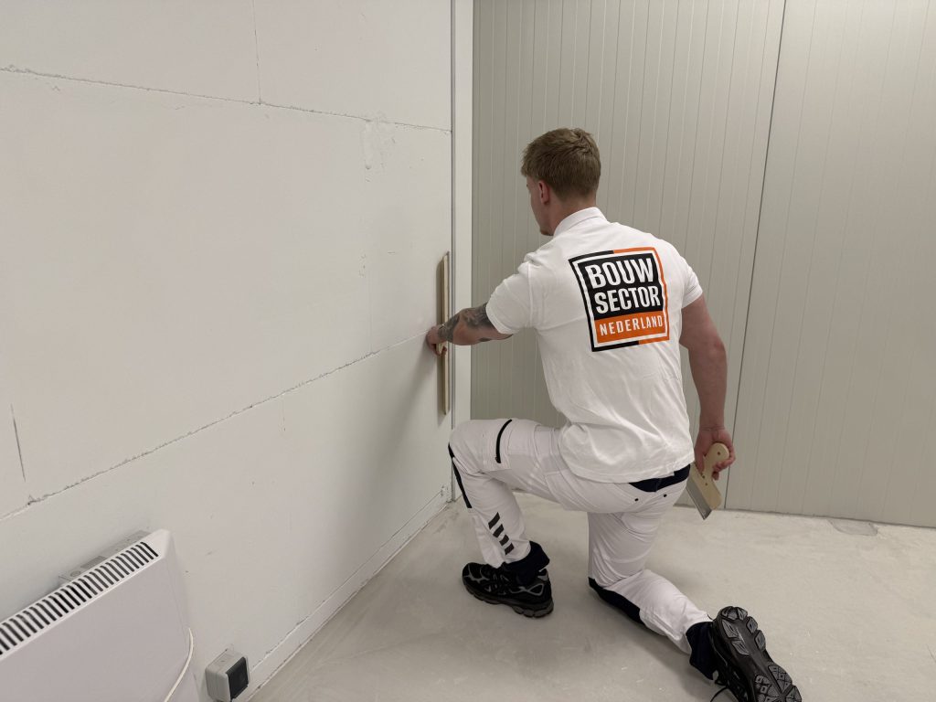 Geknielde stukadoor van Bouwsector Nederland werkt het onderste deel van een wand af